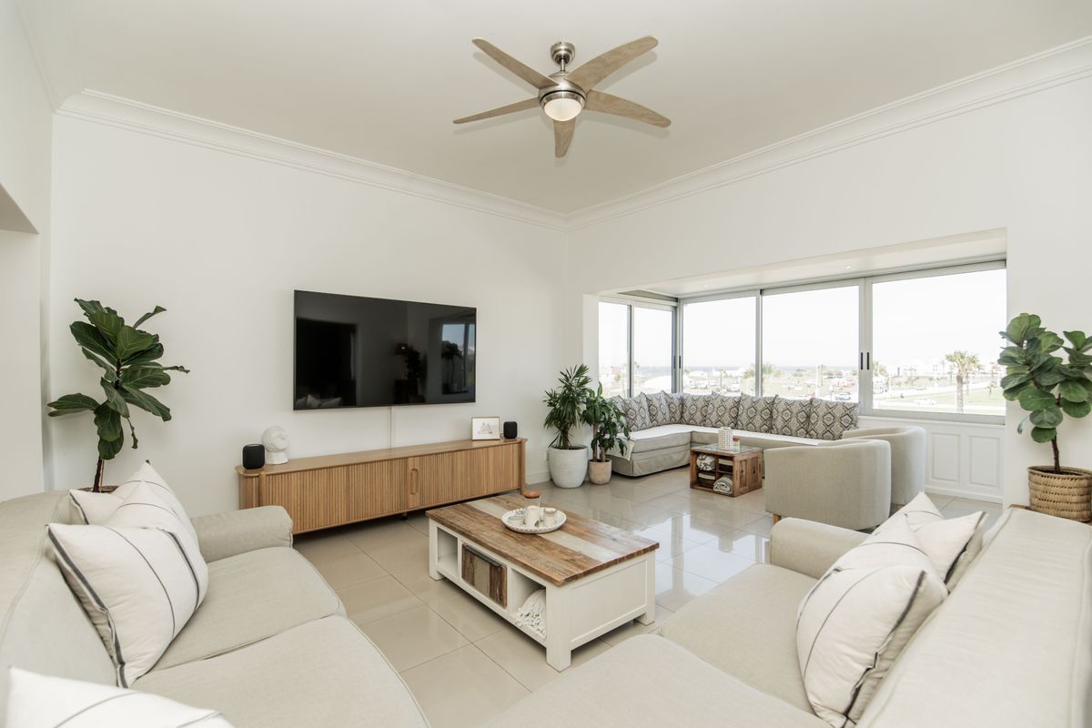 A bright and modern living room featuring tiled flooring, a ceiling fan, and large sliding glass doors that provide ample natural light.