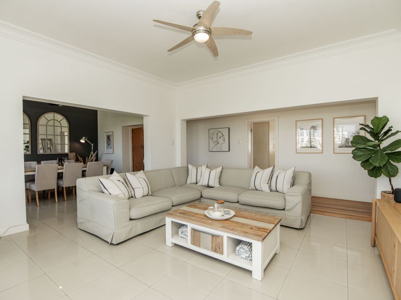 Spacious open-plan living area featuring neutral tiled flooring, modern ceiling fan, and clean white walls, seamlessly connecting to the adjacent dining space.