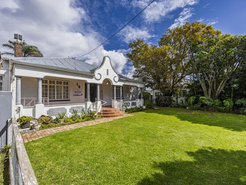 Charming front facade of a house featuring a covered porch, classic architectural details, and a well-maintained front garden with a brick pathway.