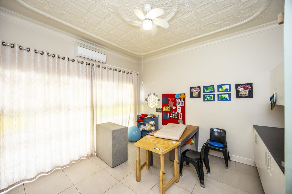 A bright bedroom featuring tiled flooring, a decorative ceiling rose with a fan, and a split system air conditioner, with access to a patio.
