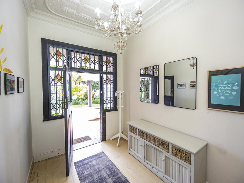 Welcoming entrance hall featuring original pressed metal ceilings, timber flooring, and a decorative stained glass front door.