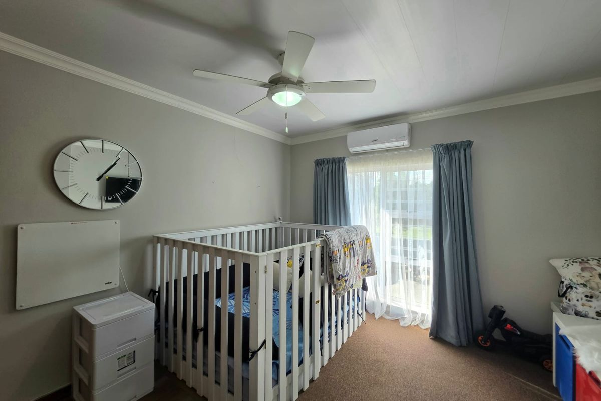A bedroom featuring a ceiling fan, split-system air conditioning unit, and sliding glass door access to the exterior.