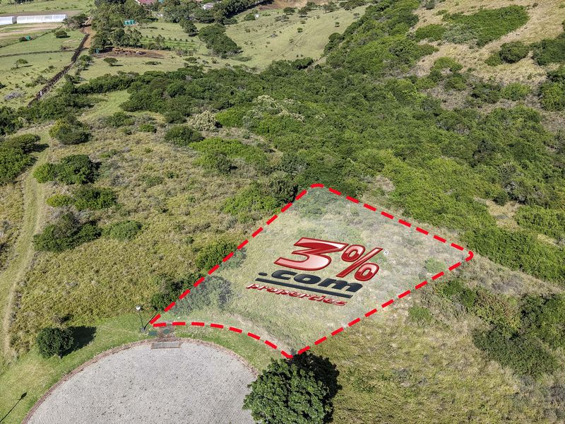 An aerial view of a vacant residential plot featuring a paved driveway and surrounding natural landscape.
