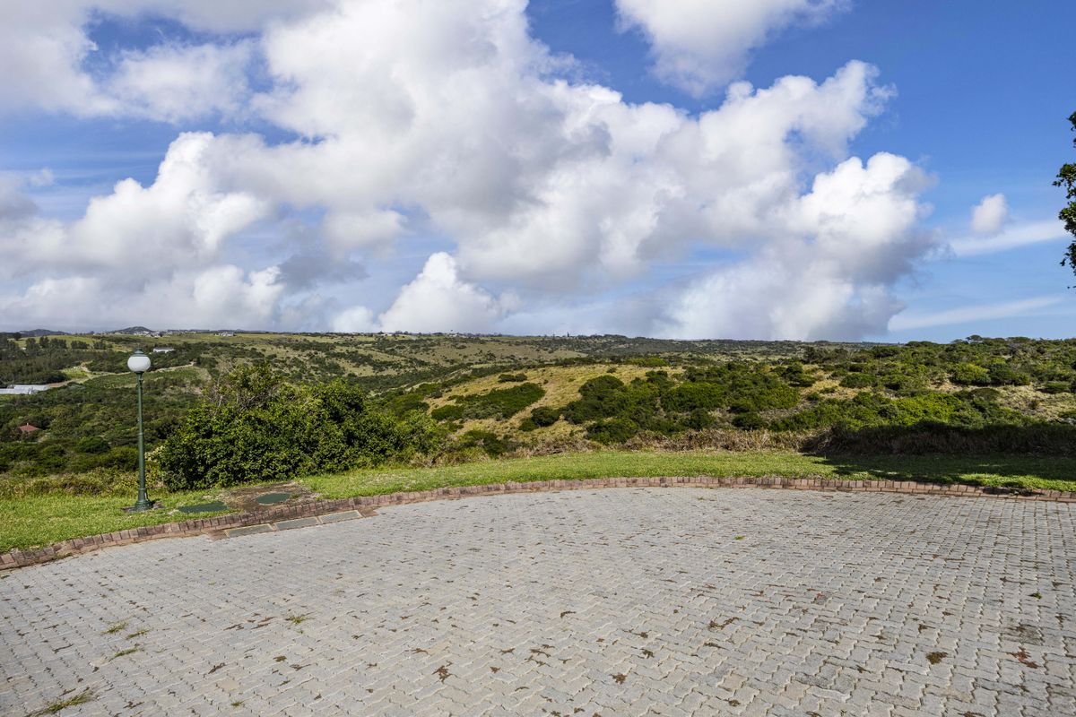 A scenic view overlooking rolling green hills and natural landscape from a paved residential driveway area.