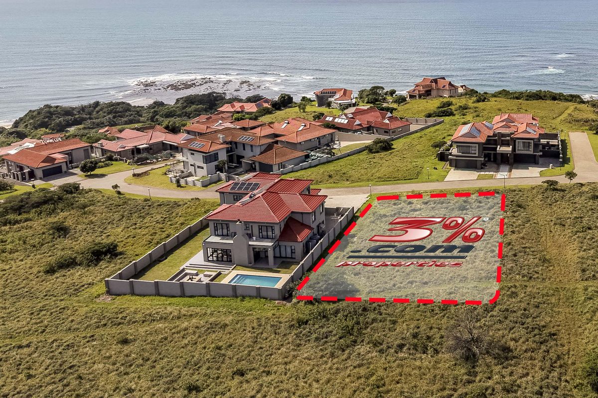 Aerial view of a vacant residential plot situated within a coastal estate, offering proximity to the ocean and established neighboring properties.