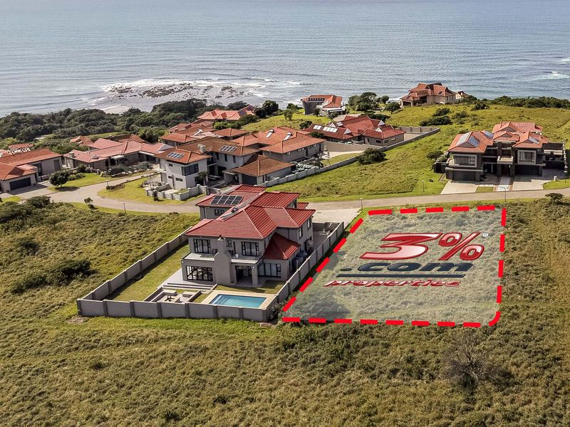 Aerial view of a vacant residential plot situated within a coastal estate, offering proximity to the ocean and established neighboring properties.