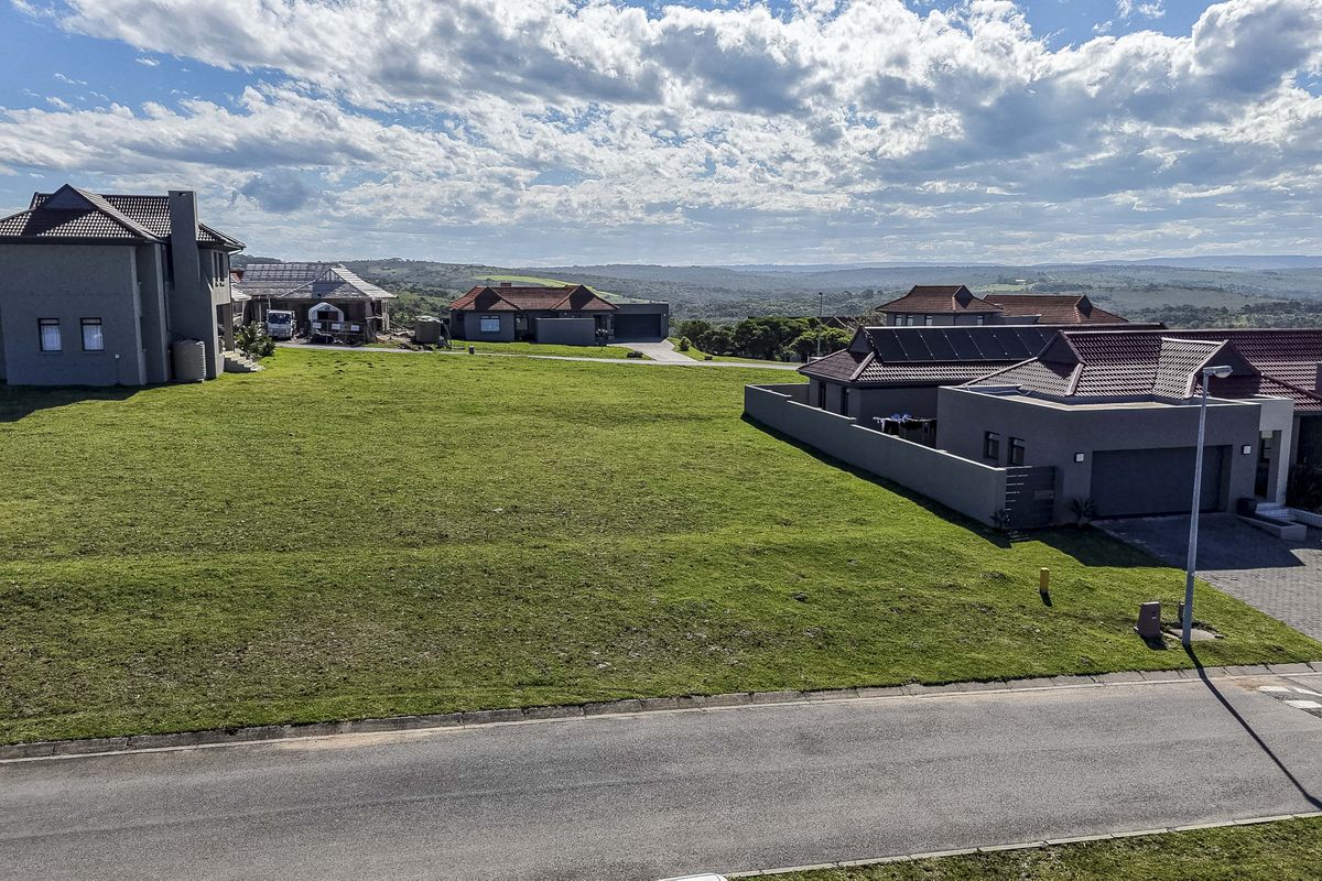 An elevated aerial view of a vacant residential plot featuring a well-maintained grass lawn, boundary walls, and surrounding neighborhood infrastructure.