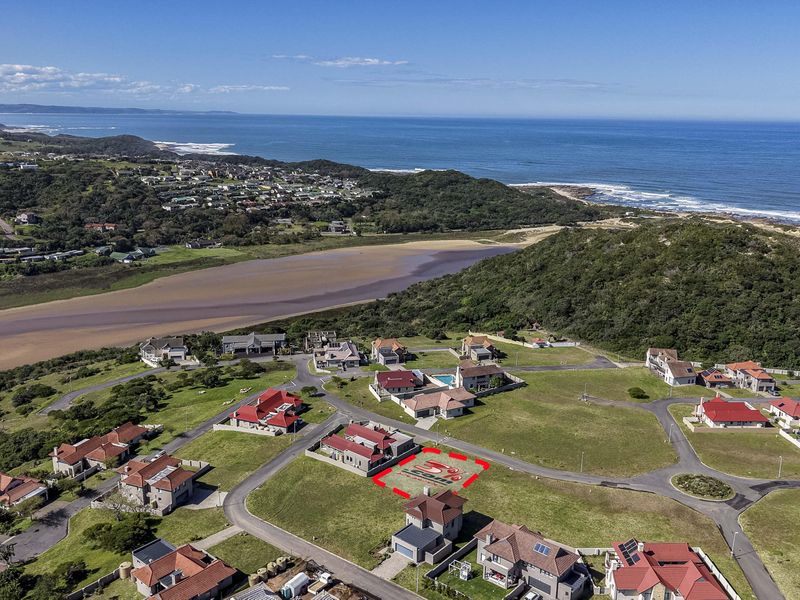 Aerial view of a vacant residential plot situated in a coastal estate, featuring established road infrastructure and proximity to the ocean.