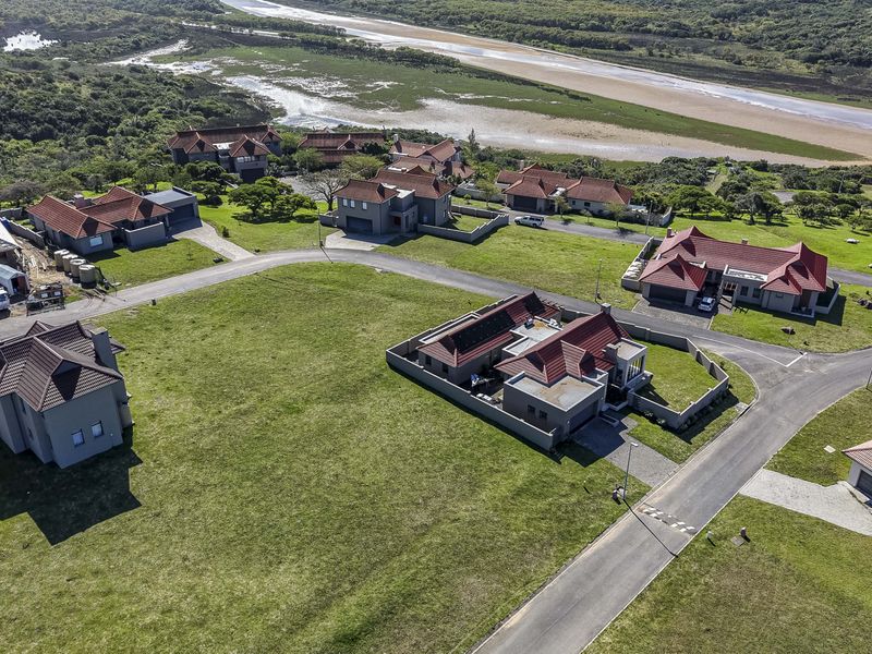 Aerial view of a residential estate featuring multiple homes, paved roads, and surrounding natural landscape.