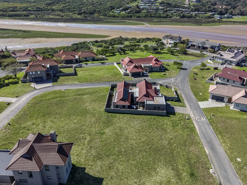 An aerial view of a residential estate featuring multiple homes, paved roads, and surrounding natural landscape.