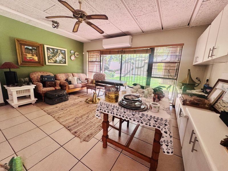 Open-plan living and kitchen area featuring tiled flooring, a ceiling fan, split-system air conditioning, and direct access to the garden through sliding glass doors.