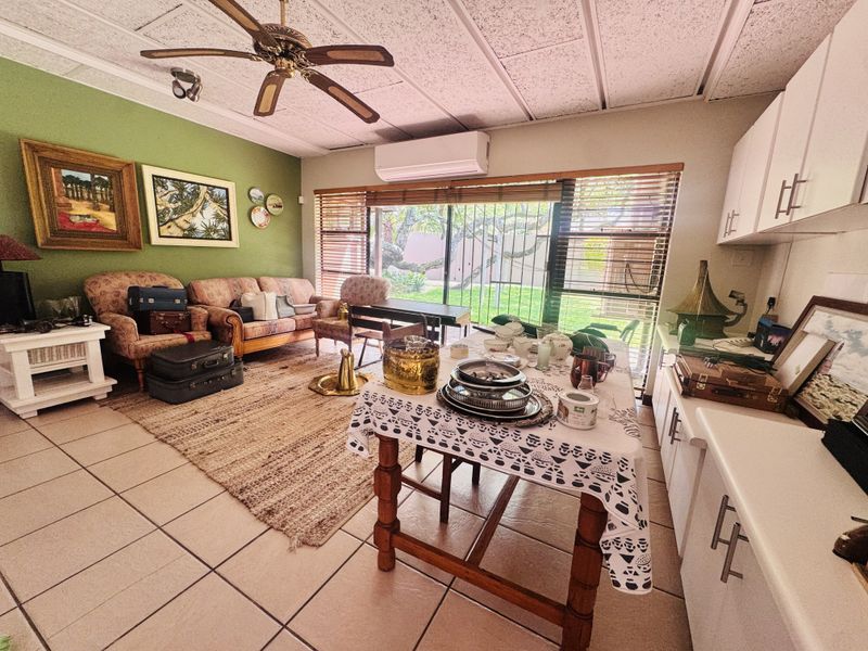Open-plan living and kitchen area featuring tiled floors, a ceiling fan, split-system air conditioning, and direct access to the garden through sliding glass doors.