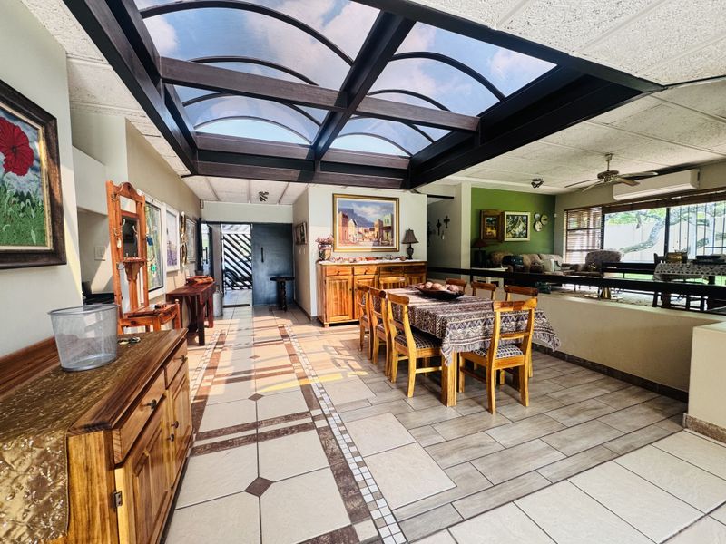 Spacious open-plan dining and living area featuring a large arched skylight, tiled flooring, and a ceiling fan, creating a bright and airy atmosphere.