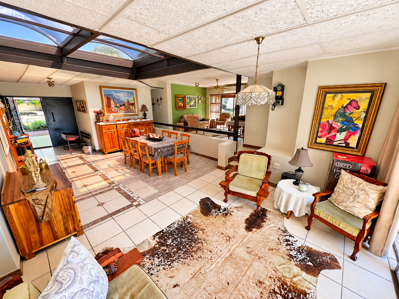 Spacious open-plan living and dining area featuring large skylights, tiled flooring, and a drop ceiling, creating a bright and connected multi-functional living space.