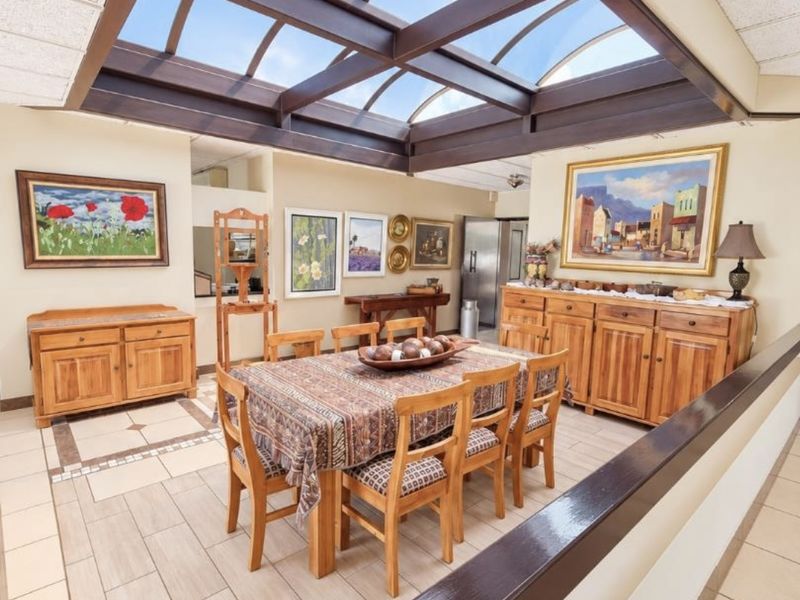 Spacious dining area featuring a large central skylight, tiled flooring, and built-in wooden cabinetry, creating a bright and inviting atmosphere.