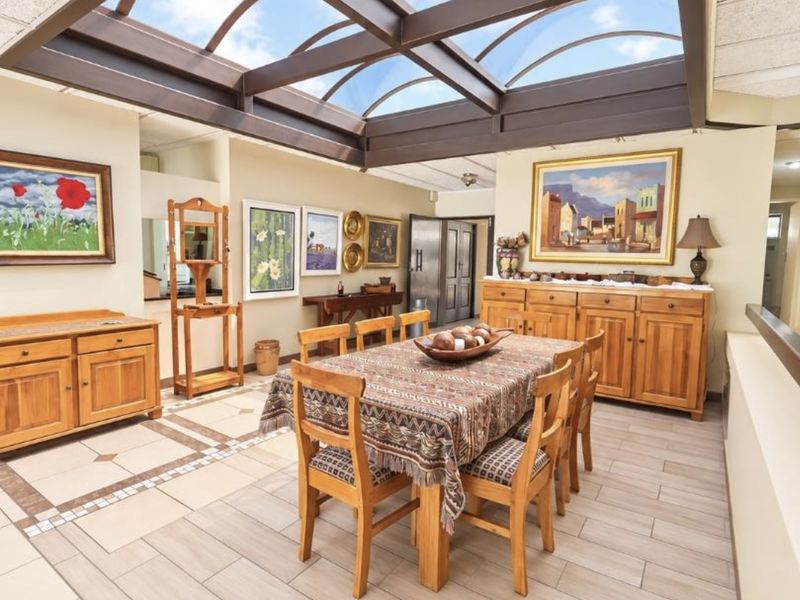 Spacious dining area featuring a large glass skylight with exposed structural beams and modern tiled flooring, creating a bright and airy atmosphere.