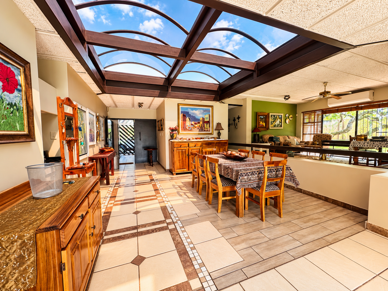 Spacious open-plan living and dining area featuring a large architectural skylight, tiled flooring, and integrated climate control.