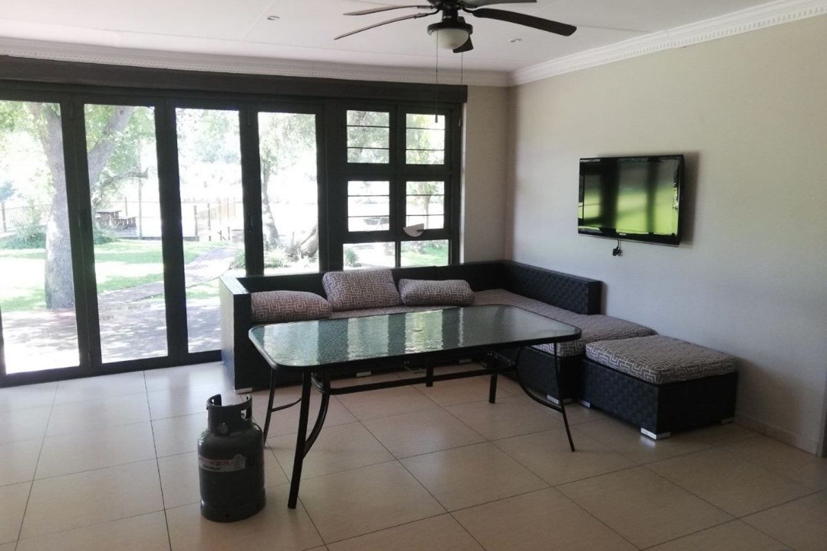 Spacious living area featuring large aluminium sliding doors providing garden access, tiled flooring, recessed lighting, and a ceiling fan.