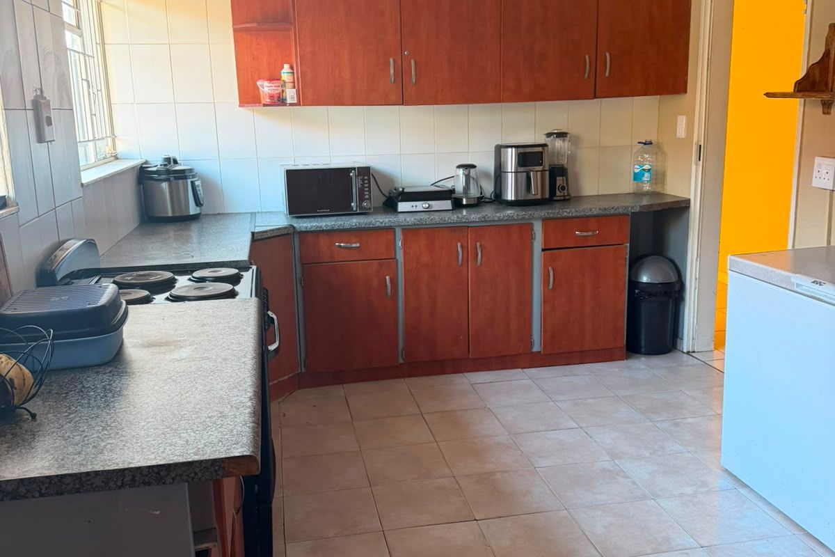 A functional kitchen featuring laminate cabinetry, ample countertop space, and ceramic tile flooring, offering a practical layout with potential for modern updates.