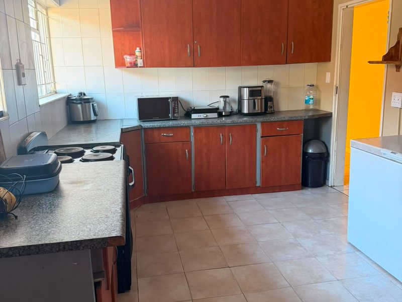 A functional kitchen featuring laminate cabinetry, ample countertop space, and ceramic tile flooring, offering a practical layout with potential for modern updates.