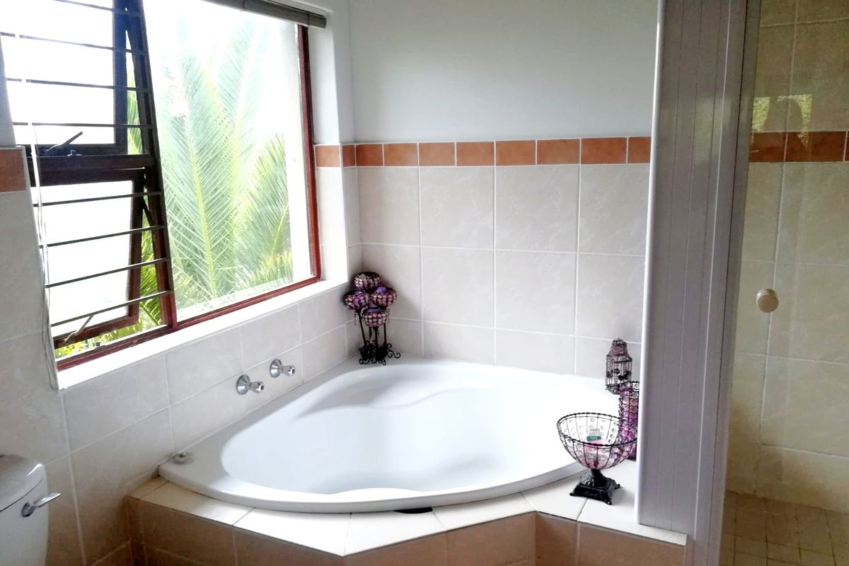 A functional bathroom featuring a corner bathtub, tiled splashback, and a separate shower enclosure with natural light from a side window.