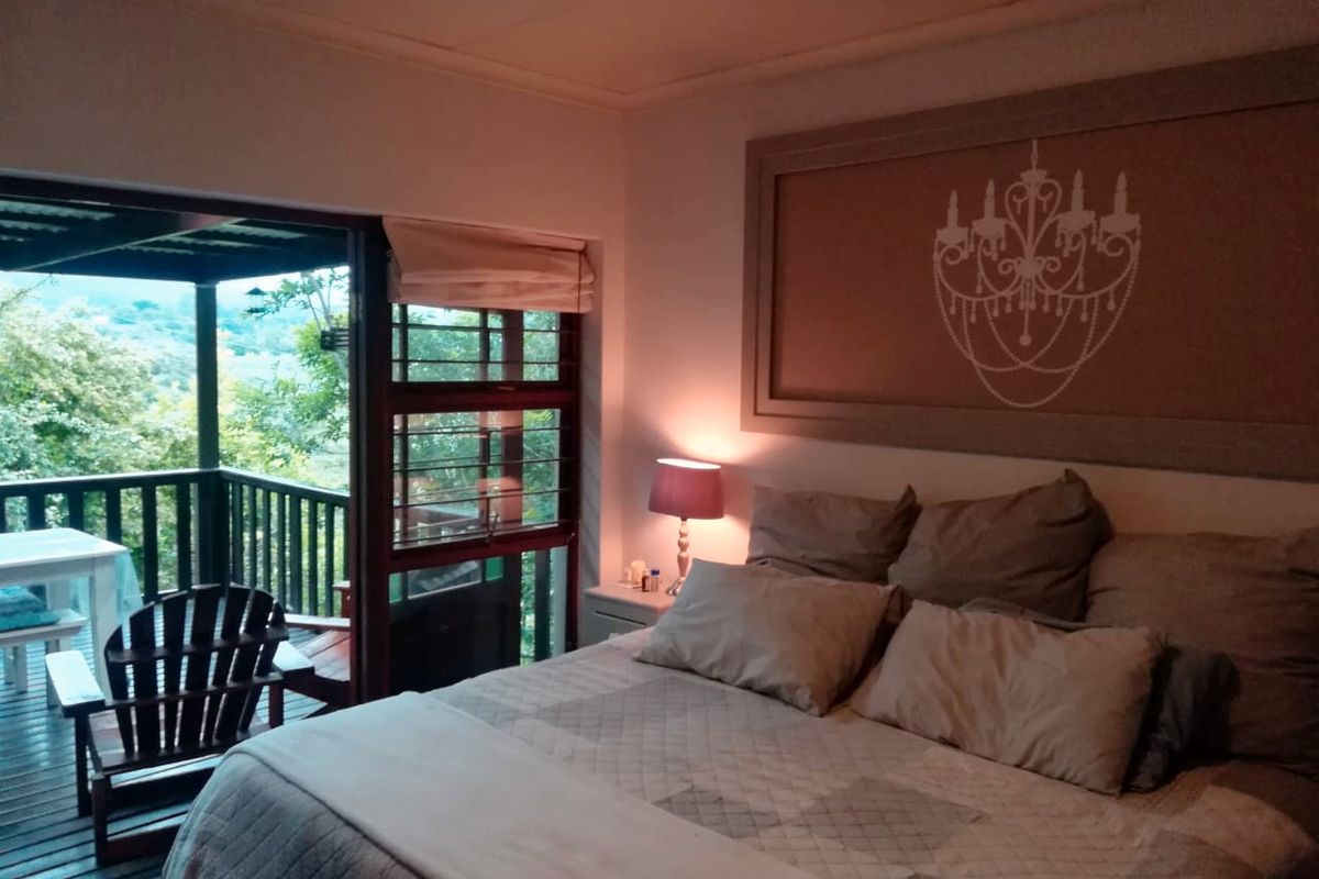 A cozy bedroom featuring direct access to an outdoor timber deck through a sliding glass door, offering a peaceful view of the surrounding greenery.