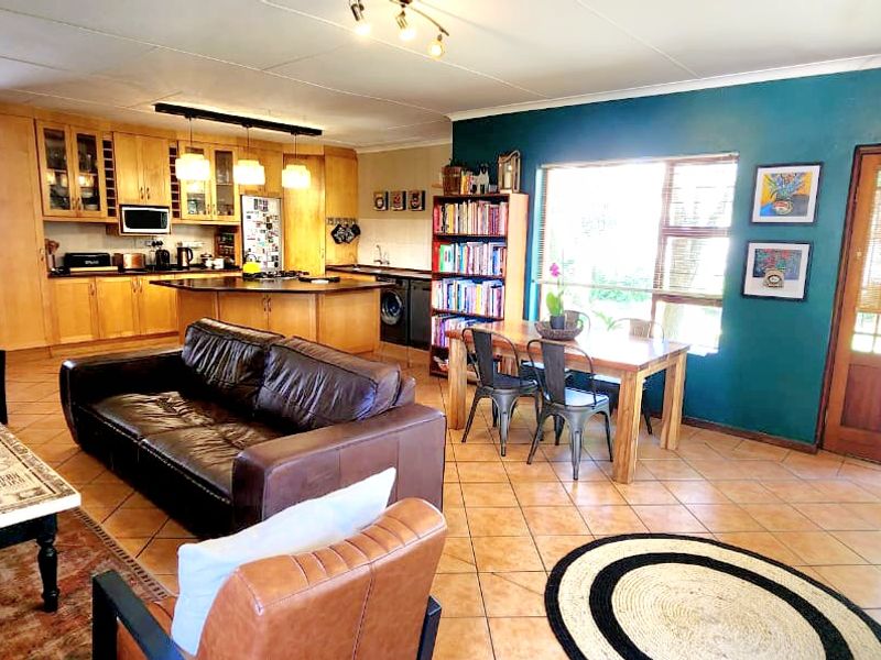 Spacious open-plan living, dining, and kitchen area featuring tiled floors, wooden cabinetry, and direct access to the outdoor space.