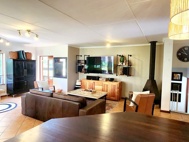 Spacious open-plan living and dining area featuring tiled flooring, a cozy freestanding fireplace, and large windows providing natural light.