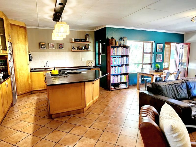 Spacious open-plan kitchen and living area featuring wooden cabinetry, a central kitchen island, and tiled flooring throughout.