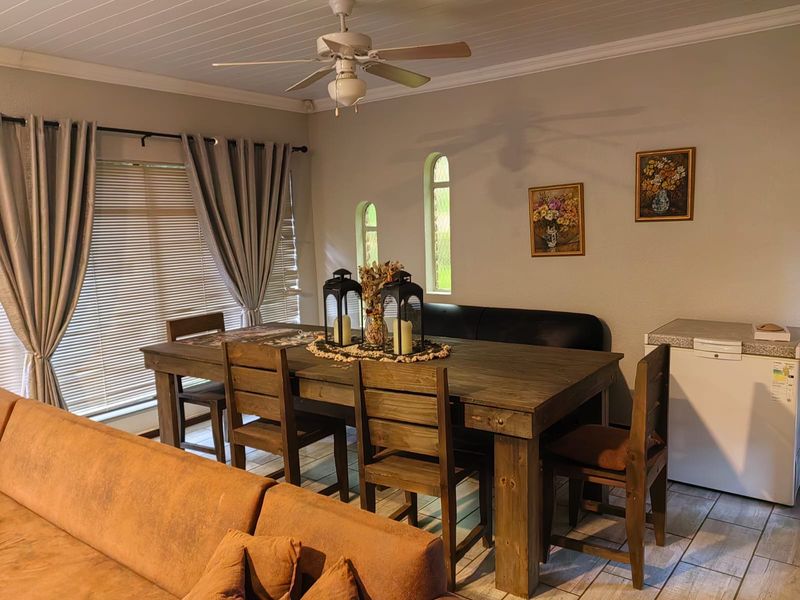 Dining area featuring tiled flooring, a ceiling fan, and distinctive arched windows, providing a functional space for meals.
