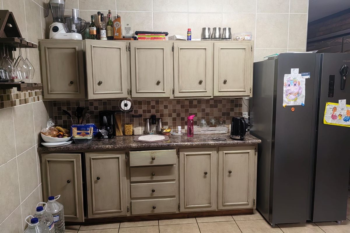 A functional kitchen area featuring neutral-toned cabinetry, laminate countertops, and a tiled backsplash with matching floor tiles.
