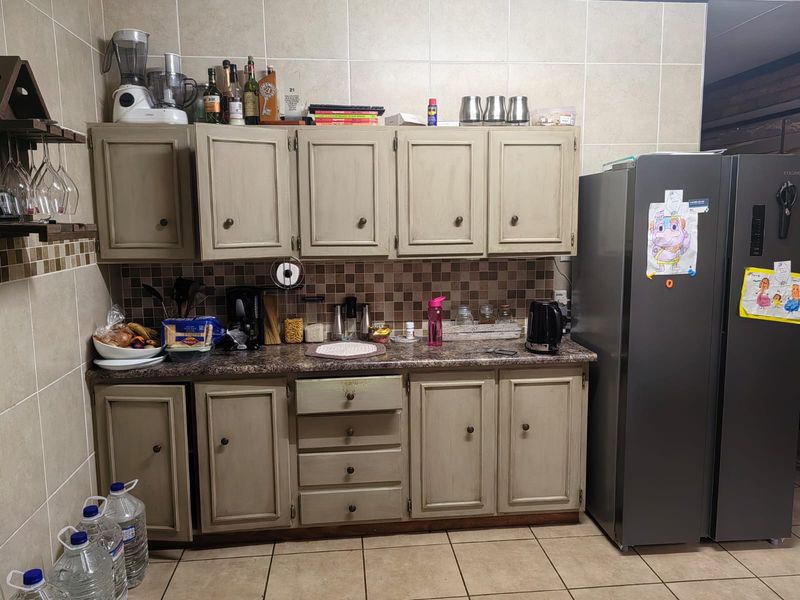 A functional kitchen area featuring neutral-toned cabinetry, laminate countertops, and a tiled backsplash with matching floor tiles.