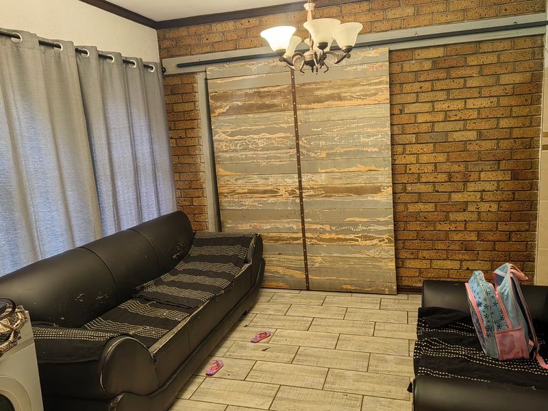 Living room featuring exposed brick walls, tiled flooring, and a rustic sliding barn door, offering a distinct industrial-style aesthetic.