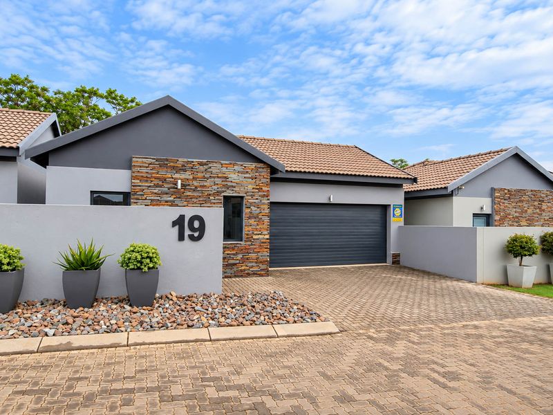 Modern front elevation featuring stone cladding, a paved driveway, and a double garage, presenting a well-maintained and contemporary residential facade.