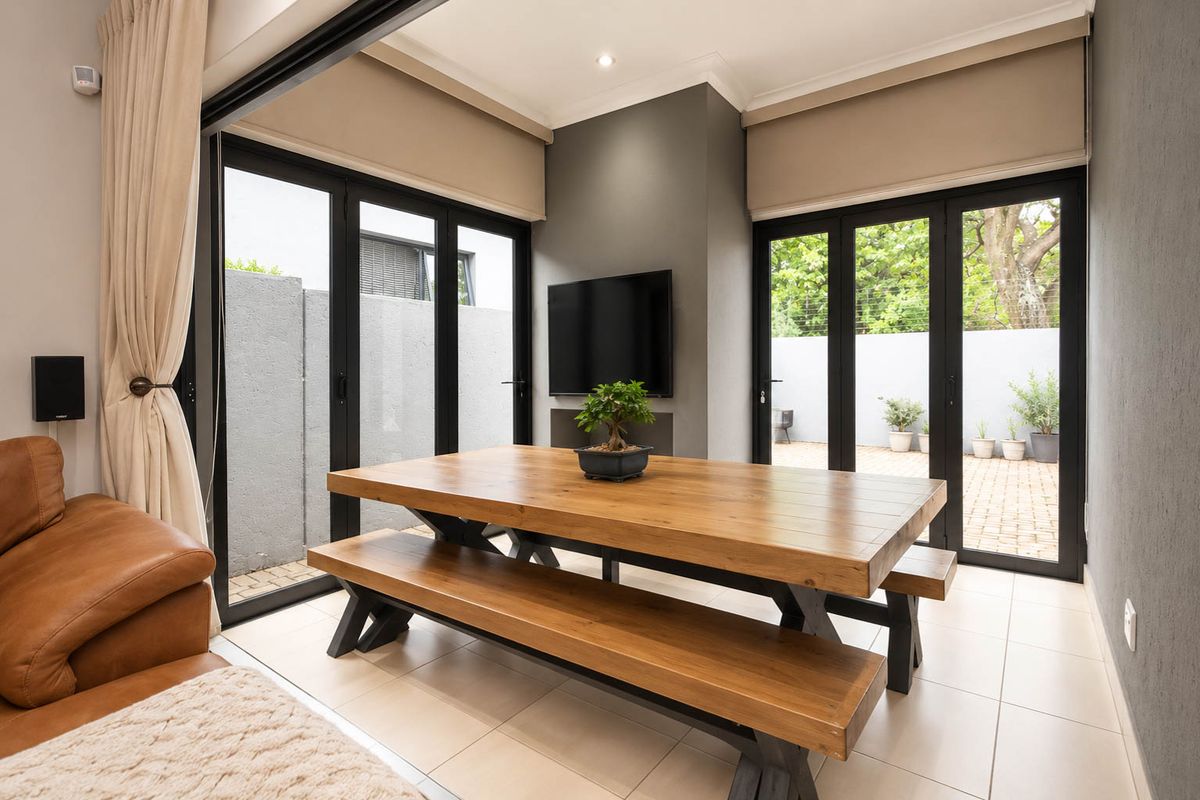 Modern living area featuring large black aluminium stacker doors that open onto a paved patio, providing seamless indoor-outdoor flow and abundant natural light.