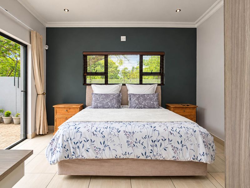 A well-maintained bedroom featuring tiled flooring, recessed downlights, and a sliding glass door providing direct access to an outdoor patio area.