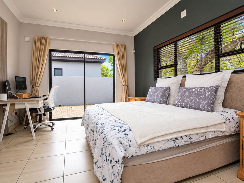 A well-maintained bedroom featuring tiled flooring, recessed downlights, and a sliding glass door providing direct access to the exterior patio area.