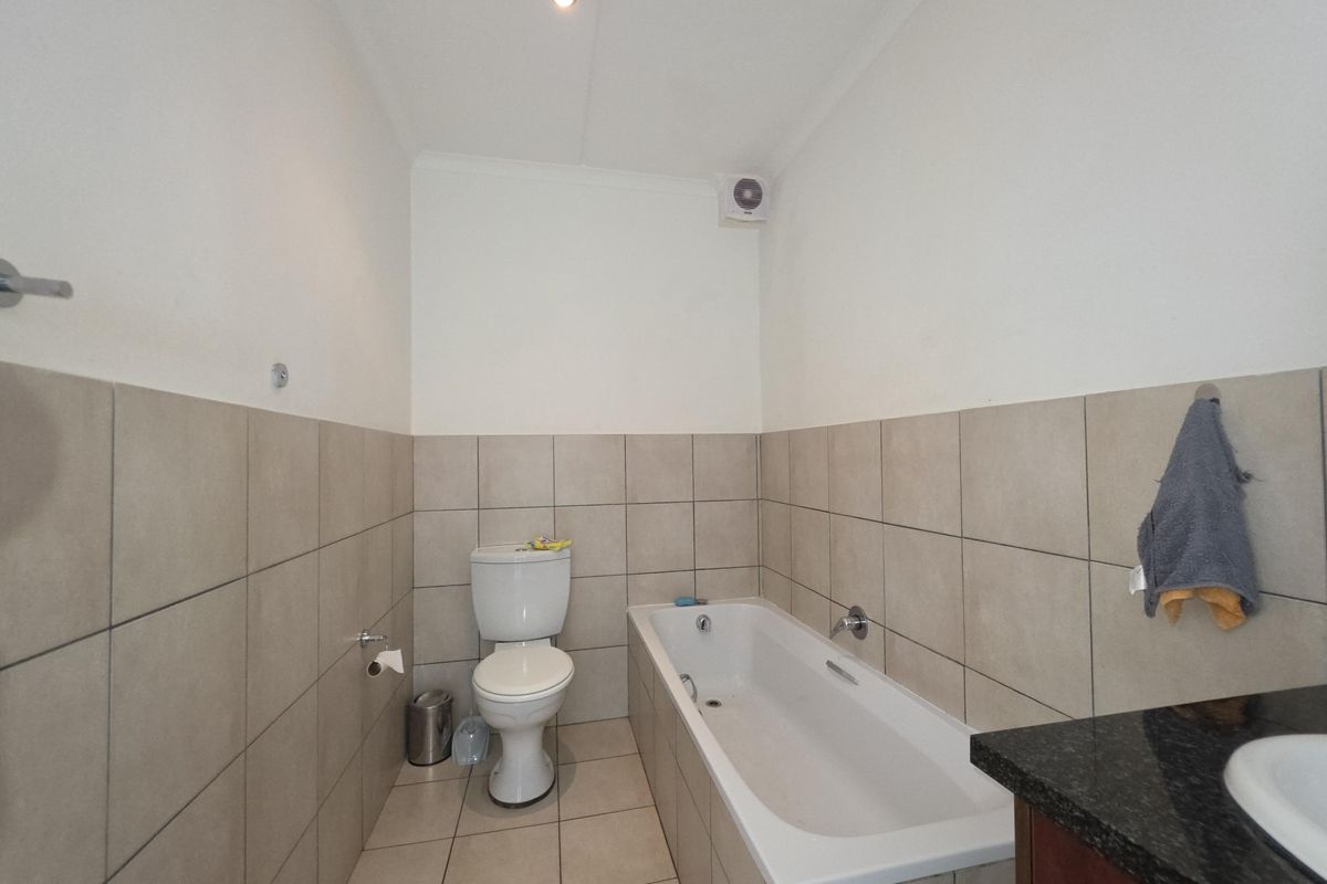 A clean, functional bathroom featuring a bathtub, toilet, and vanity with tiled finishes throughout.