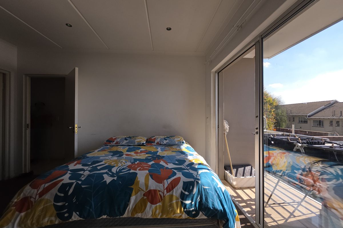 A bedroom featuring sliding glass doors that open onto a private balcony, providing natural light and outdoor access.