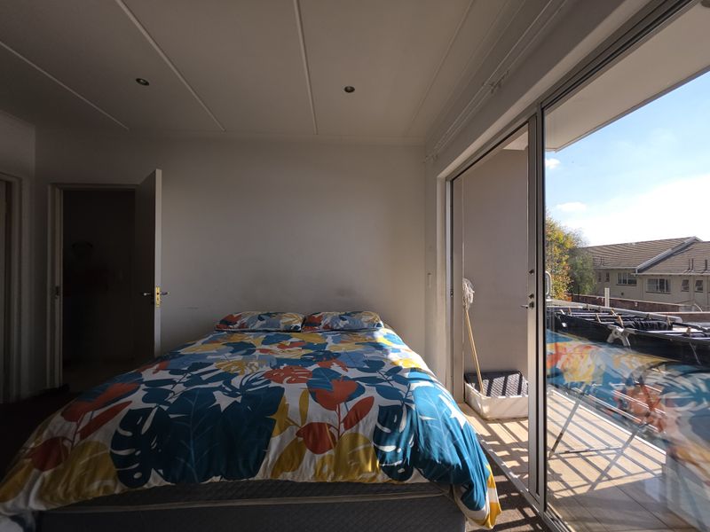 A bedroom featuring sliding glass doors that open onto a private balcony, providing natural light and outdoor access.