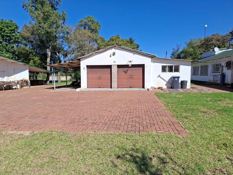 A detached double garage with a paved driveway and an adjacent covered carport area on a small holding property.