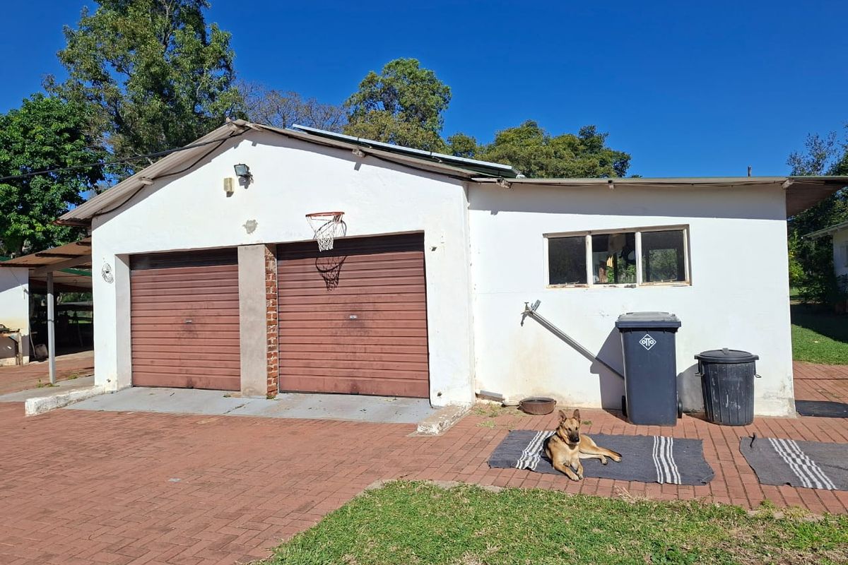 A detached double garage with brick paving and exterior wall-mounted lighting, showing signs of wear on the facade and garage doors.