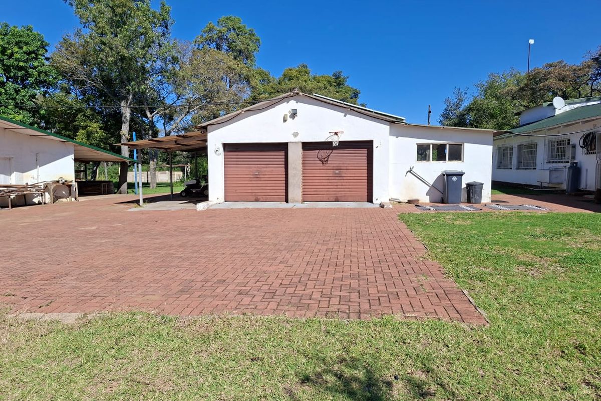 A detached double garage with a paved driveway and an adjacent covered carport area on a small holding property.