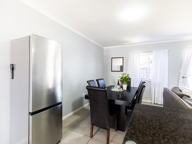 Open plan living and dining area featuring neutral wall tones and tiled flooring, providing a functional space for daily living.