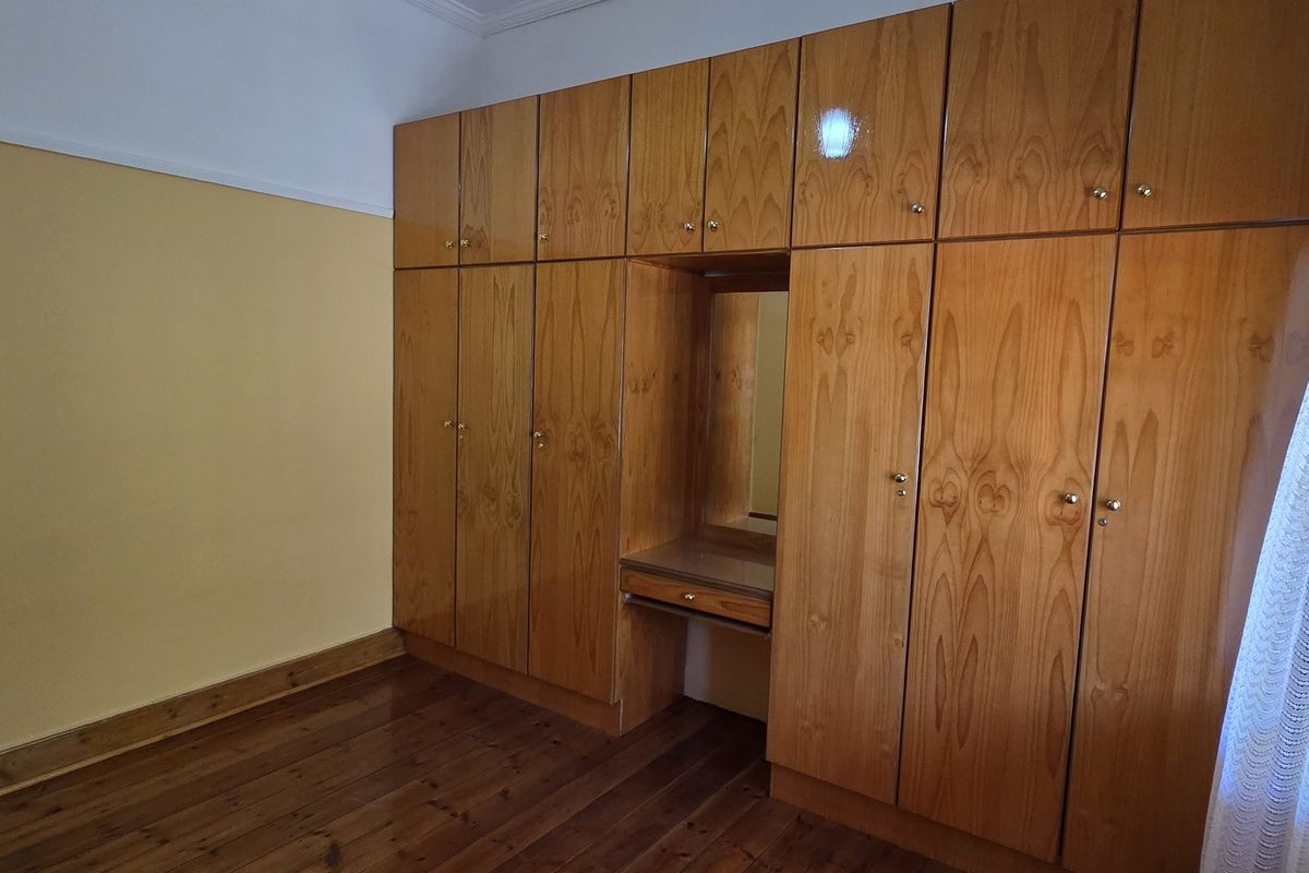 A bedroom featuring extensive built-in wooden cabinetry with an integrated vanity and polished hardwood flooring.