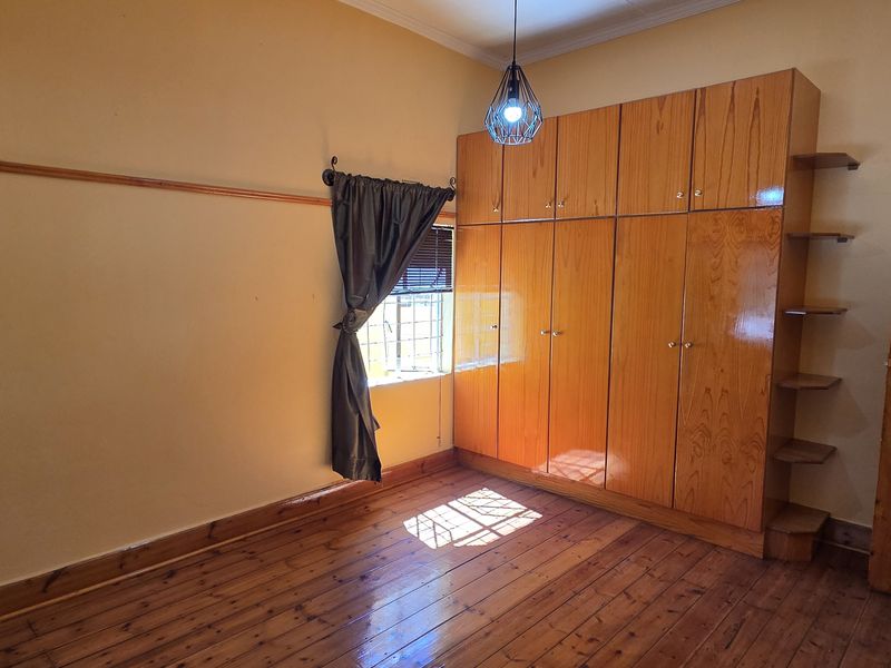 A bedroom featuring original wooden flooring, built-in wooden cabinetry, and a classic wooden door, offering a solid foundation for renovation.
