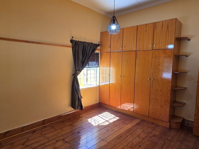 A bedroom featuring polished wooden flooring, built-in wooden cabinetry with integrated shelving, and a classic wooden door.