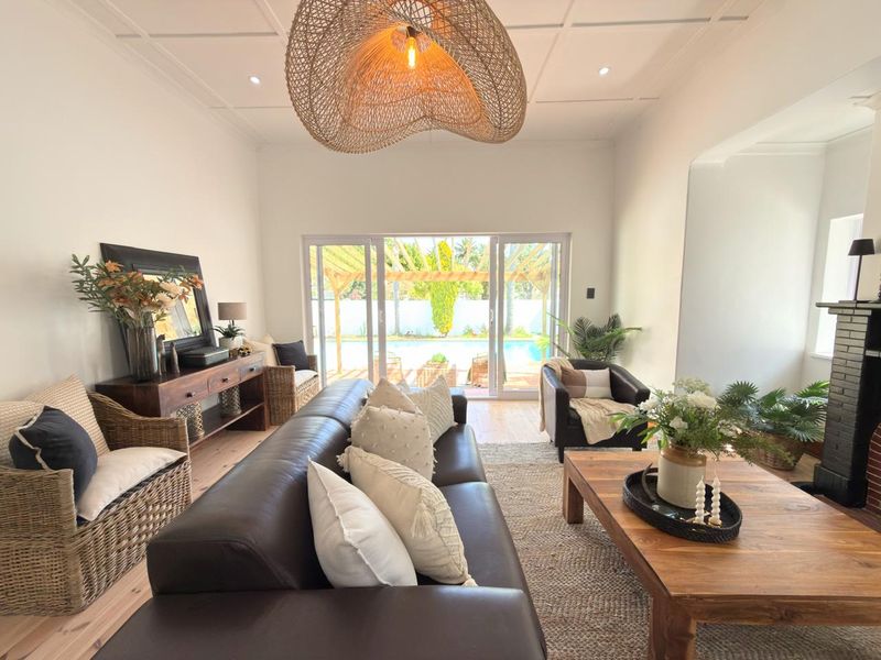 Spacious living room featuring a coffered ceiling, recessed lighting, and large sliding glass doors that provide direct access to the outdoor pool area.