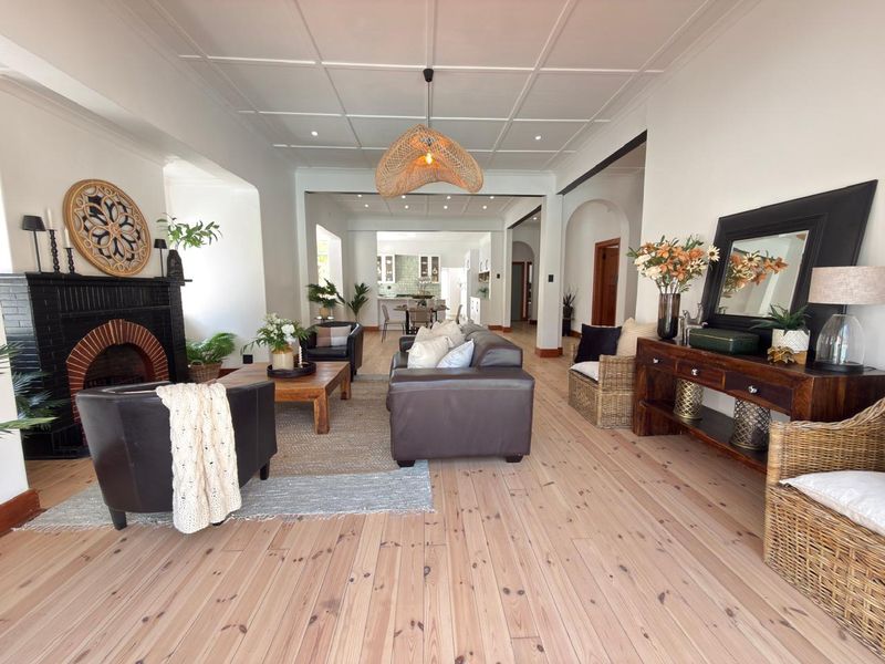 Spacious open-plan living area featuring timber flooring, a classic brick fireplace, and elegant coffered ceilings, flowing seamlessly into the kitchen space.