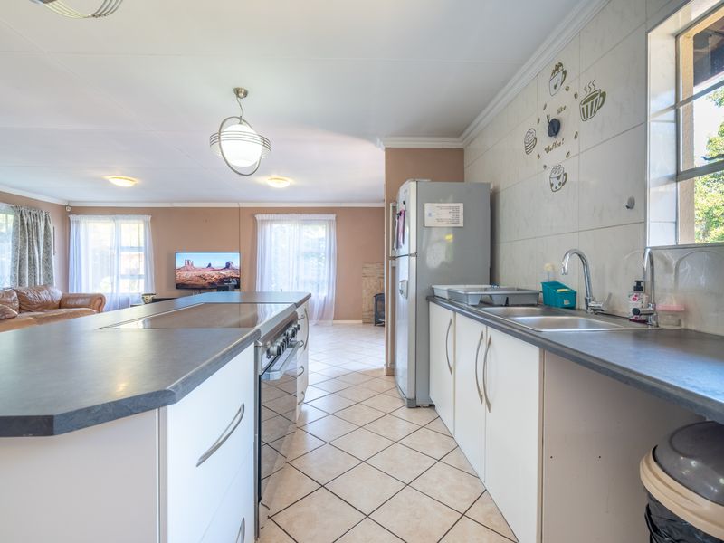 Open plan kitchen and living area featuring a central island with built-in oven, tiled flooring, and neutral wall finishes.